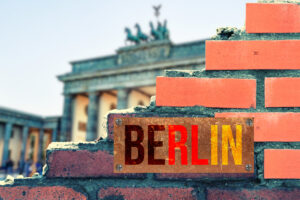 A wall, a view of the Brandenburg Gate and a sign Berlin